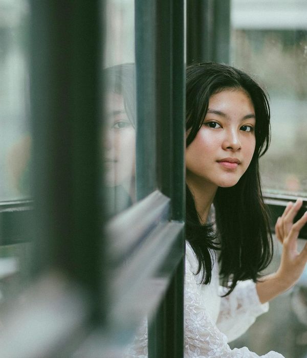 Person peacefully looking out a window with a focused gaze.